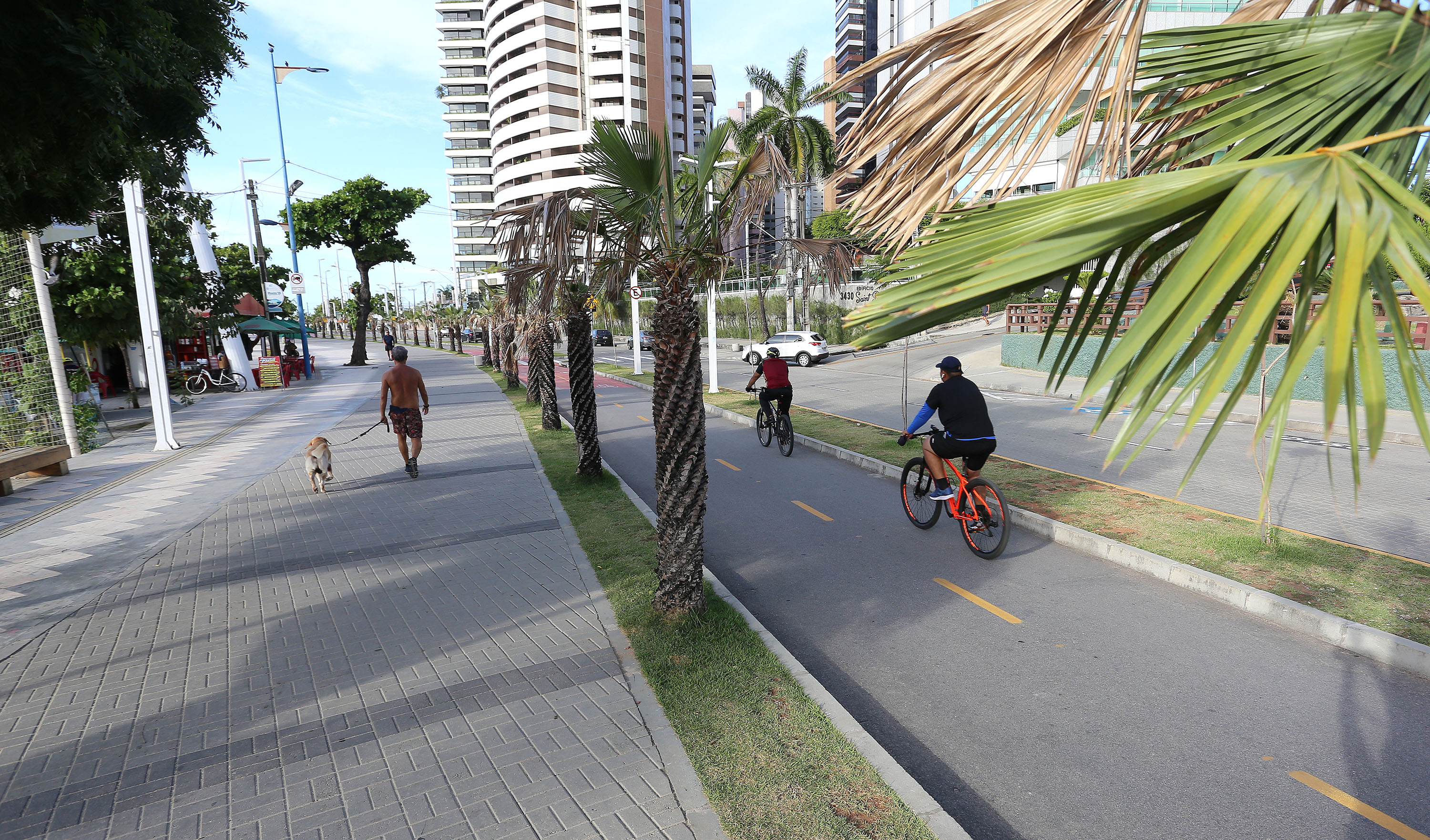 a foto mostra ciclistas na ciclovia e pedestres na calçada na avenida beira-mar